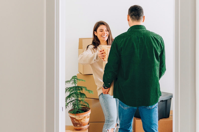 Kaksi henkilöä purkavat muuttolaatikoita asunnossa.