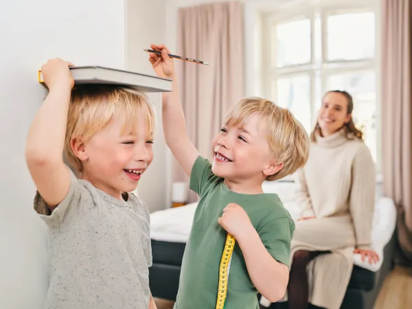Lapset merkitsevät pituuksiaan seinälle äidin katsellessa.