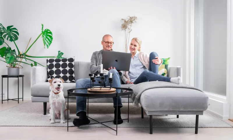Kaksi aikusta istuu sohvalla ja katsovat kannettavaa tietokonetta