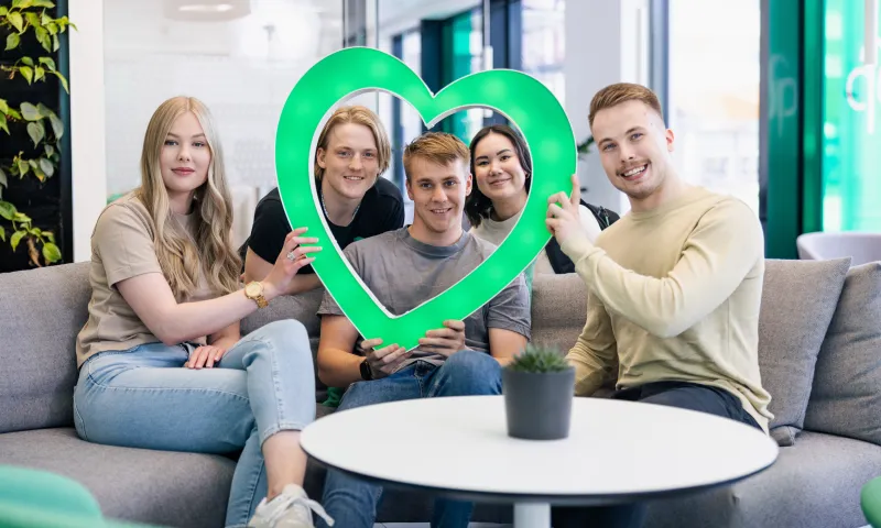 Nuoret istuvat sohvalla ja rekvisiittana vihreä valosydän