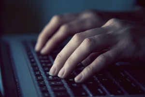 Henkilön sormet kannettavan tietokoneen näppäimistöllä.