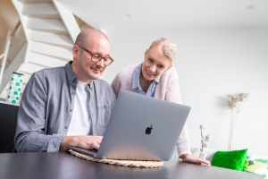 Pariskunta täyttää lainahakemusta tietokoneella.