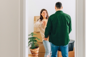 Kaksi henkilöä purkavat muuttolaatikoita asunnossa.