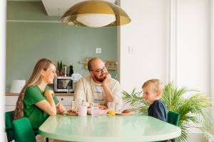 Perhe keskustelee keittiön pöydän ääressä.