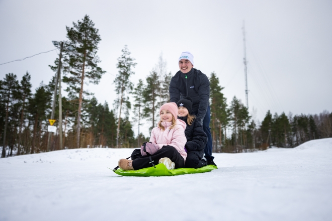 Mies pulkkamäessä lasten kanssa.