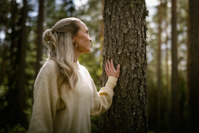 Nainen koskettaa puun runkoa