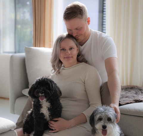 Noora perhekuvassa puolison ja koirien kanssa.